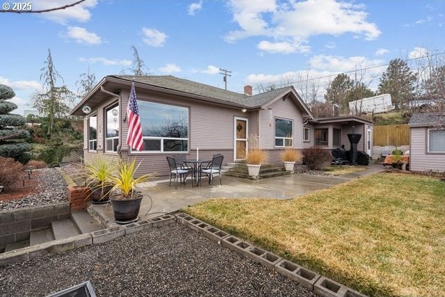 rear view of house featuring a patio, an outdoor structure, and a lawn