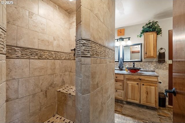 bathroom featuring vanity, tiled shower, and tile walls