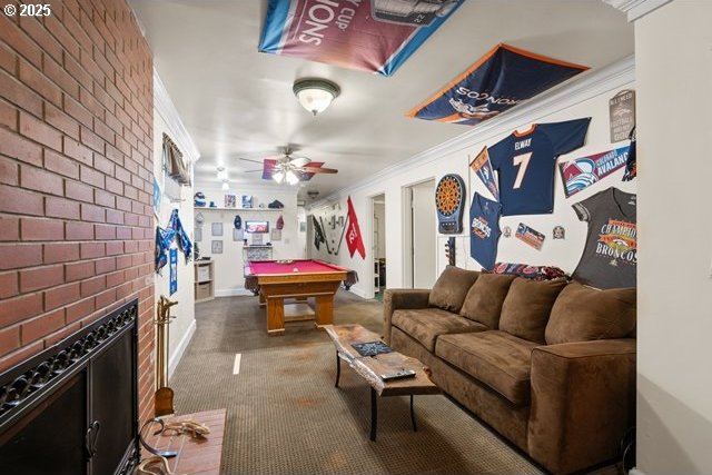 rec room featuring carpet flooring, ornamental molding, pool table, ceiling fan, and a brick fireplace