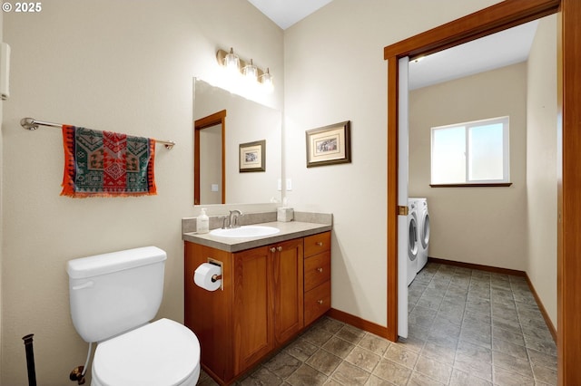 bathroom featuring washer and dryer, vanity, toilet, stone finish floor, and baseboards