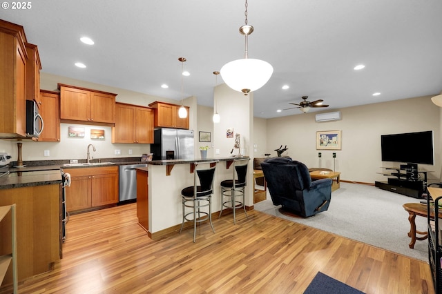 kitchen with dark countertops, a sink, stainless steel appliances, open floor plan, and a kitchen bar