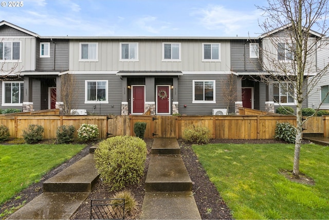 townhome / multi-family property featuring a fenced front yard, a gate, a front lawn, and board and batten siding