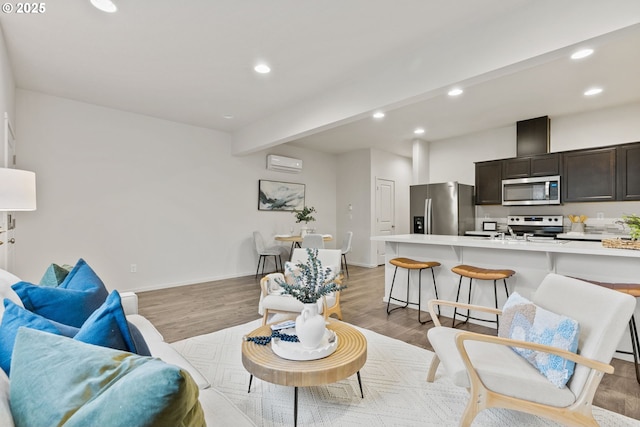 living room with baseboards, a wall unit AC, light wood-style flooring, beamed ceiling, and recessed lighting