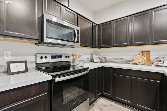 kitchen featuring light countertops, appliances with stainless steel finishes, light wood-type flooring, and dark brown cabinetry