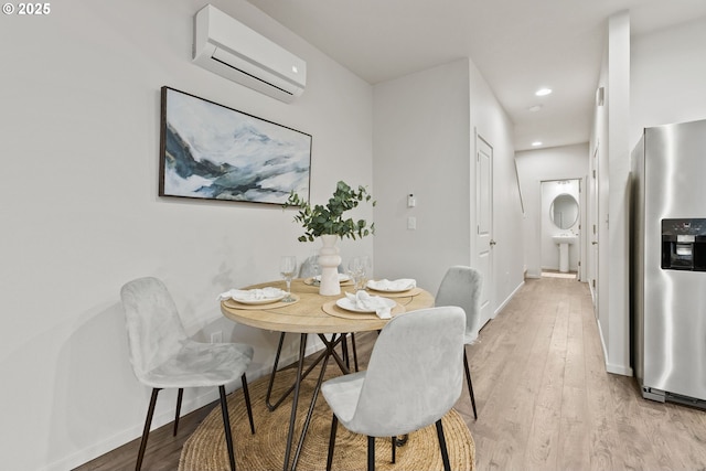 dining space with recessed lighting, a wall unit AC, light wood-style flooring, and baseboards