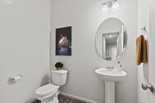 bathroom with toilet, a sink, baseboards, and wood finished floors