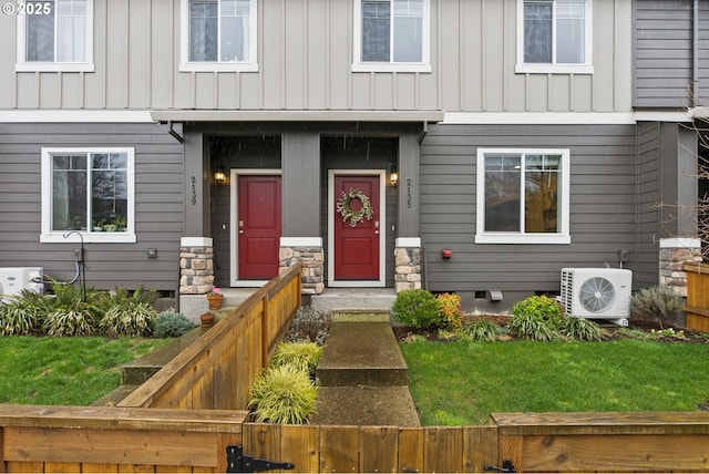 doorway to property featuring crawl space, ac unit, stone siding, and board and batten siding