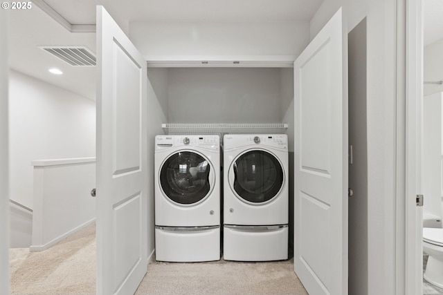 washroom featuring light colored carpet, laundry area, visible vents, and washing machine and clothes dryer