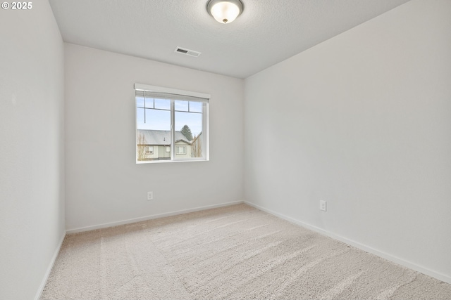 carpeted empty room featuring a textured ceiling, visible vents, and baseboards