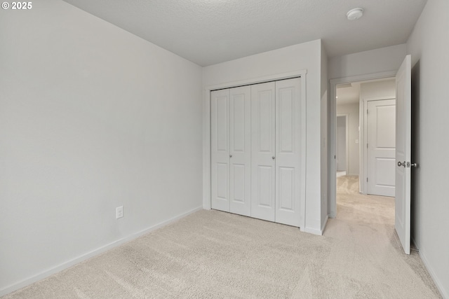 unfurnished bedroom with baseboards, a closet, and light colored carpet