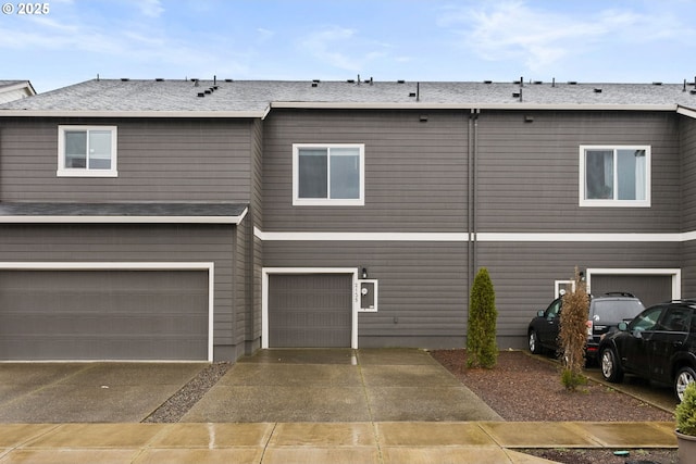 view of front facade with a garage, concrete driveway, and a shingled roof