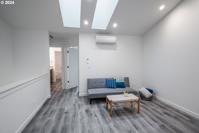 sitting room with wood-type flooring, a wall unit AC, and a skylight