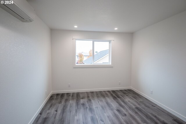 empty room featuring dark hardwood / wood-style flooring and a wall mounted AC