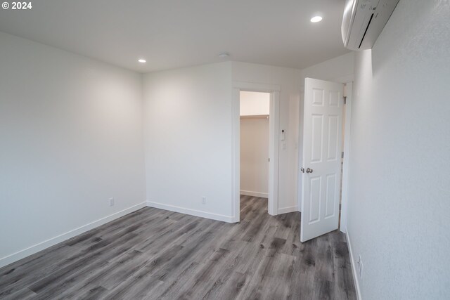 spare room featuring hardwood / wood-style flooring and an AC wall unit