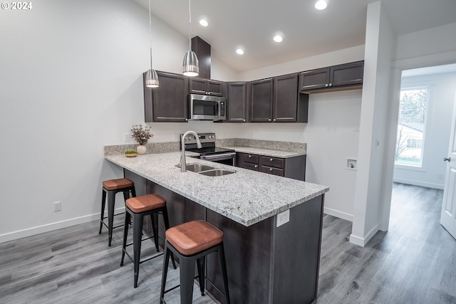 kitchen featuring hanging light fixtures, dark brown cabinets, stainless steel appliances, a kitchen breakfast bar, and vaulted ceiling