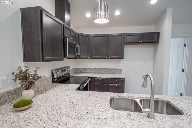 kitchen featuring sink, appliances with stainless steel finishes, hanging light fixtures, dark brown cabinets, and light stone countertops