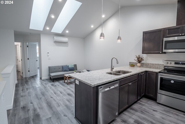 kitchen featuring sink, a skylight, a wall unit AC, stainless steel appliances, and kitchen peninsula