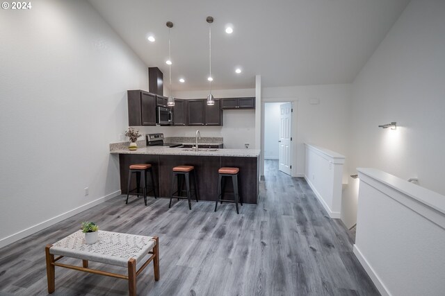 kitchen featuring appliances with stainless steel finishes, pendant lighting, a kitchen bar, kitchen peninsula, and light wood-type flooring