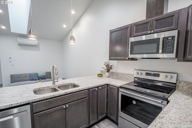 kitchen featuring stainless steel appliances, hanging light fixtures, sink, and a wall mounted AC