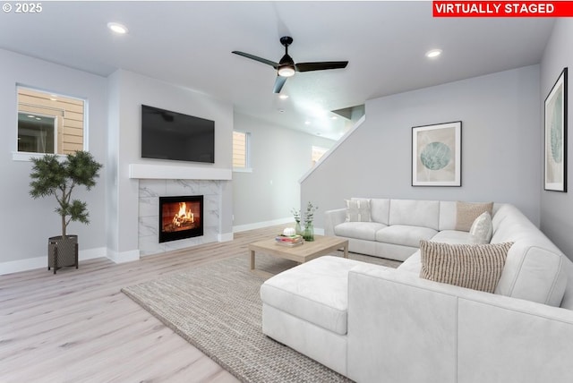 living room featuring light hardwood / wood-style flooring, a fireplace, and ceiling fan