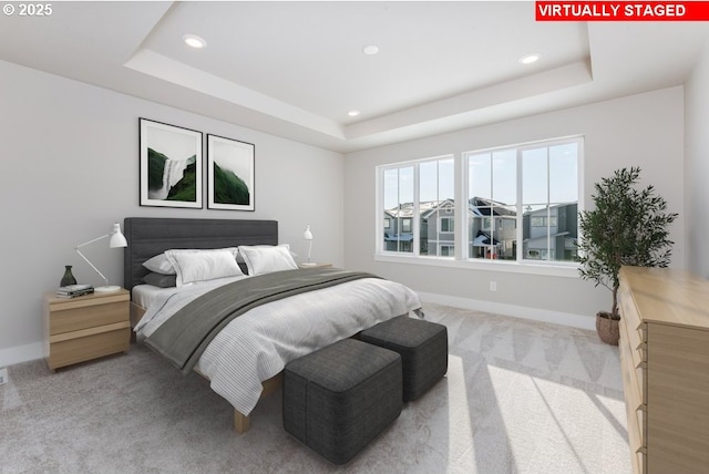 bedroom with light carpet and a tray ceiling