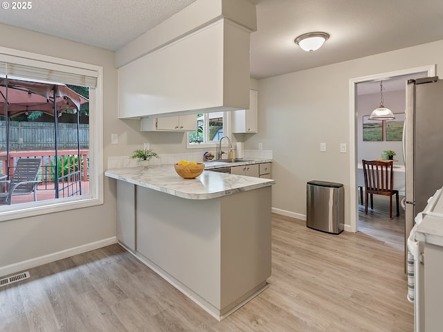 8320 SW Chelan St, Tualatin, OR 97062 - kitchen with freestanding refrigerator, light countertops, a peninsula, and light wood-type flooring