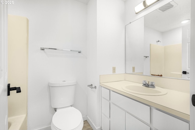 bathroom with vanity, toilet, baseboards, and visible vents