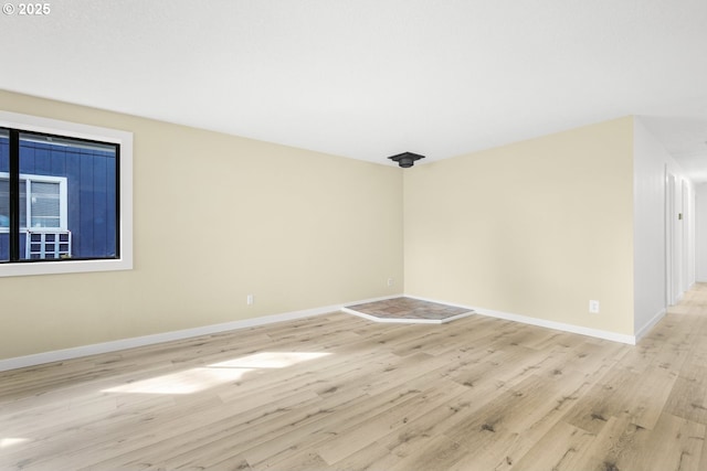 unfurnished room with light wood-type flooring and baseboards