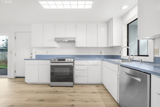 kitchen featuring light wood-type flooring, under cabinet range hood, a sink, appliances with stainless steel finishes, and white cabinets