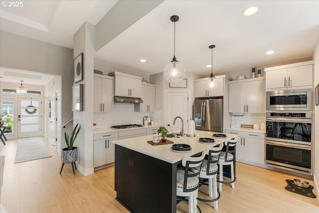 12505 NE 102nd Way, Vancouver, WA 98682 - kitchen featuring appliances with stainless steel finishes, under cabinet range hood, light countertops, decorative backsplash, and pendant lighting