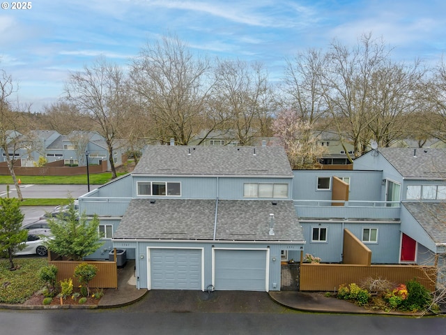 exterior space featuring a balcony, an attached garage, driveway, and roof with shingles