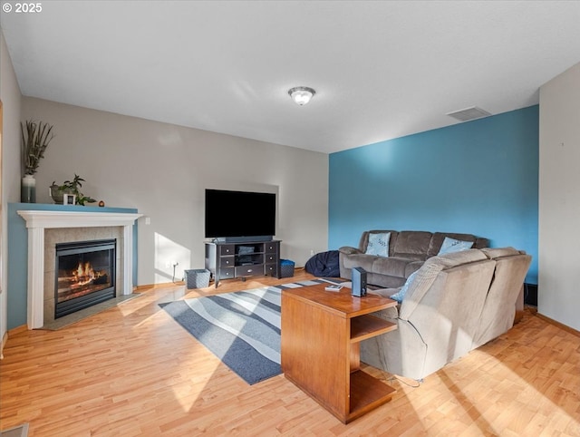 living room featuring a tiled fireplace and light wood-type flooring