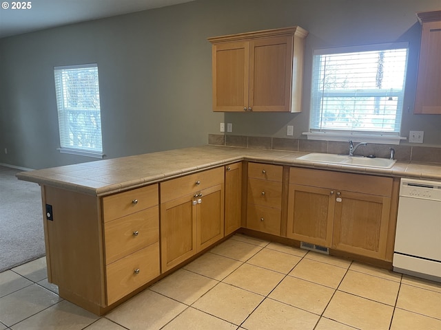 kitchen with a healthy amount of sunlight, dishwasher, sink, and kitchen peninsula