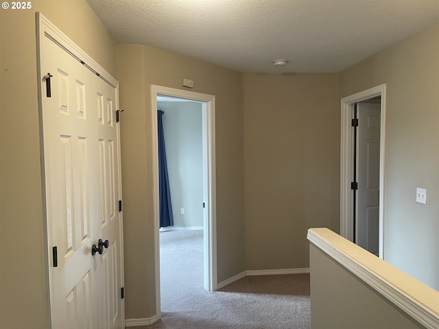 hall featuring light colored carpet and a textured ceiling