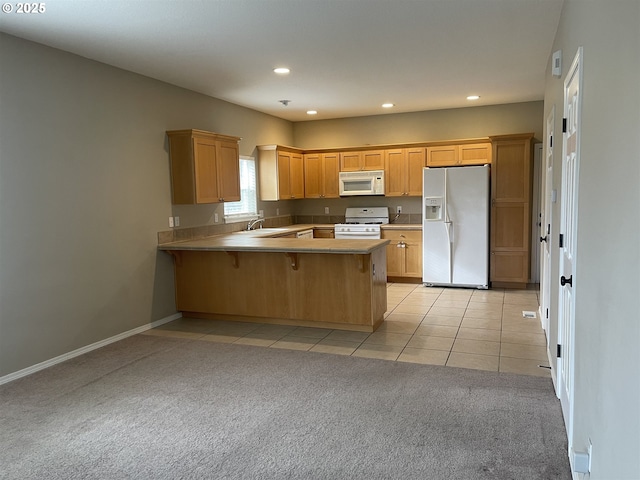 kitchen with sink, white appliances, a kitchen bar, light tile patterned flooring, and kitchen peninsula