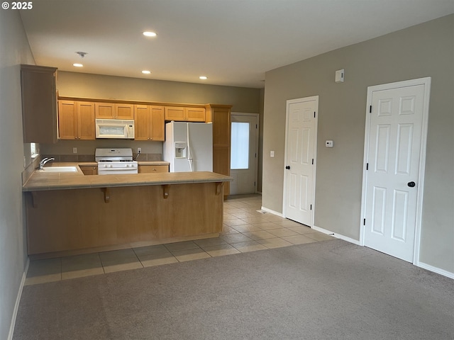 kitchen featuring sink, a kitchen bar, light colored carpet, kitchen peninsula, and white appliances