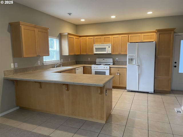 kitchen featuring sink, white appliances, kitchen peninsula, and light tile patterned floors