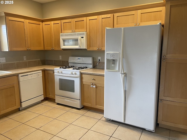 kitchen with light tile patterned flooring, sink, and white appliances