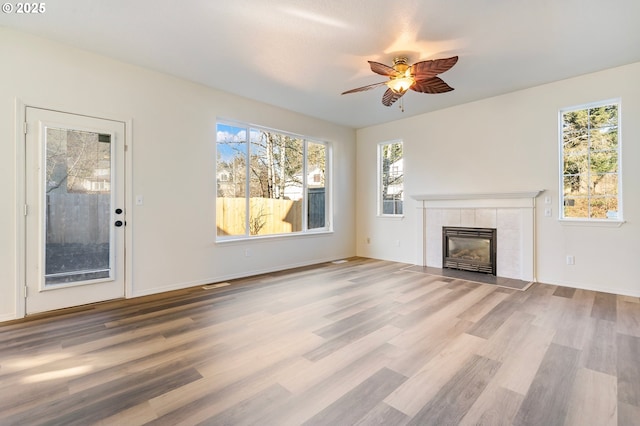 unfurnished living room with ceiling fan, a fireplace, and light wood-type flooring