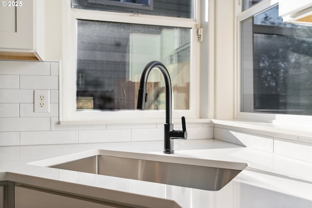 room details with white cabinetry, sink, and decorative backsplash