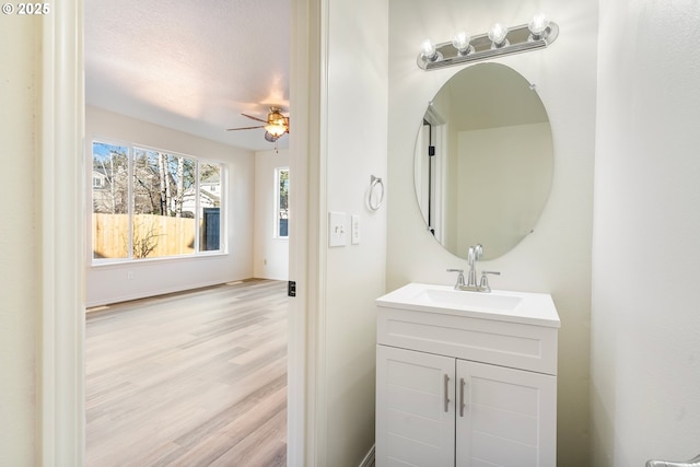 bathroom with hardwood / wood-style flooring, vanity, ceiling fan, and a textured ceiling