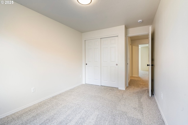 unfurnished bedroom featuring light carpet and a closet