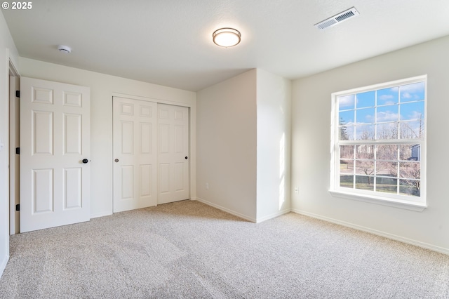 unfurnished bedroom featuring light colored carpet and a closet