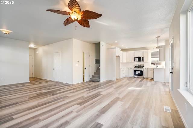 unfurnished living room featuring sink, ceiling fan, and light hardwood / wood-style flooring