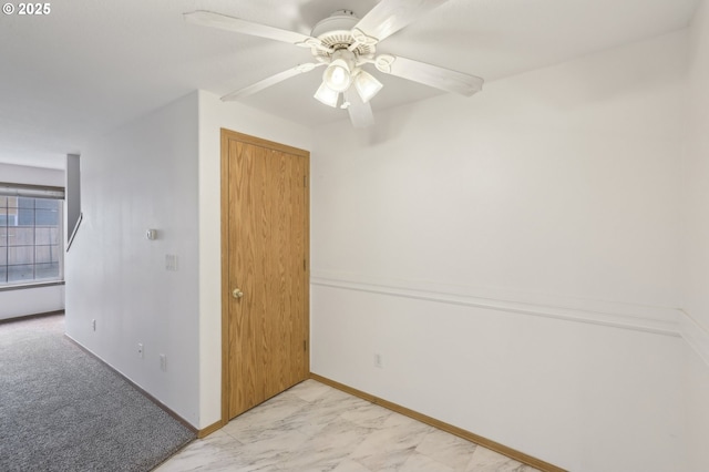 empty room featuring baseboards, a ceiling fan, and marble finish floor