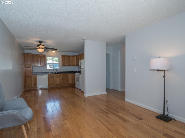 2712 SE 138th Ave Unit 53, Portland, OR 97236 - kitchen with white appliances, a textured ceiling, ceiling fan, light wood finished floors, and brown cabinets