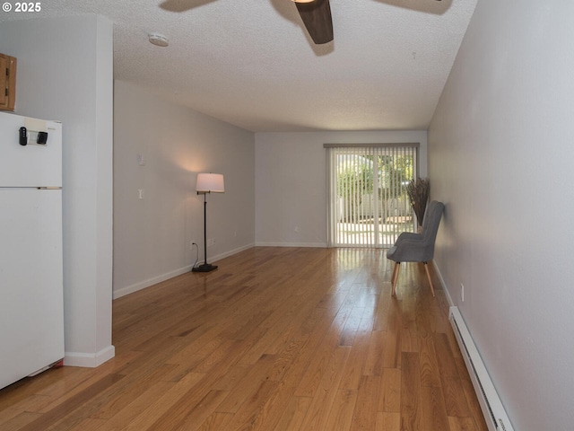 2712 SE 138th Ave Unit 53, Portland, OR 97236 - unfurnished room with a baseboard radiator, ceiling fan, light wood-type flooring, and a textured ceiling