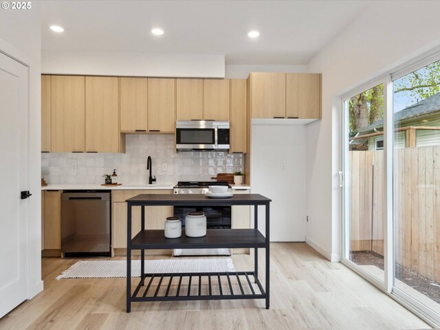1534 N Schofield St, Portland, OR 97217 - kitchen with appliances with stainless steel finishes, light brown cabinets, light wood finished floors, tasteful backsplash, and recessed lighting