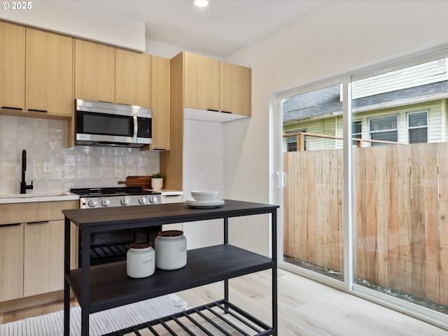 1534 N Schofield St, Portland, OR 97217 - kitchen featuring stainless steel appliances, light brown cabinets, a sink, light wood finished floors, and backsplash