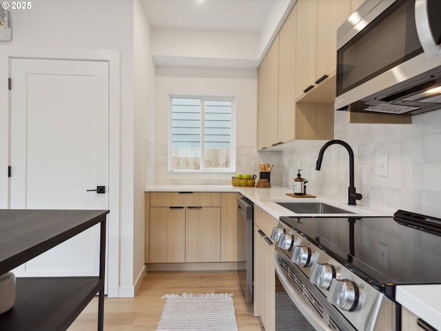 1534 N Schofield St, Portland, OR 97217 - kitchen featuring appliances with stainless steel finishes, a sink, light wood-type flooring, decorative backsplash, and light countertops